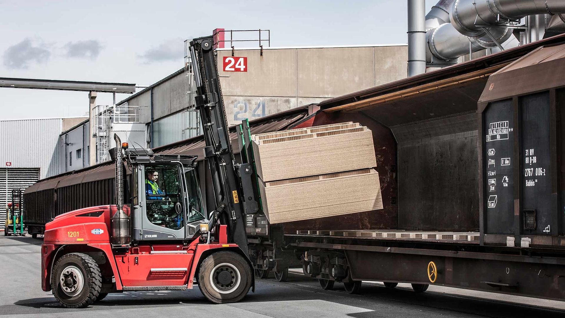 Ein Gabelstapler bestückt einen Schiebewandwagen mit Holzbauelementen.