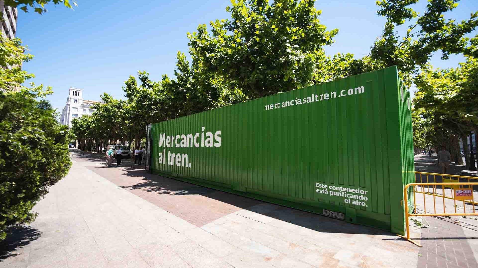 The green container labelled Mercancias al tren is located in a park in Spain.