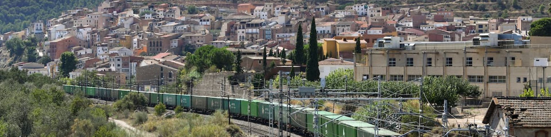 Ein Zug fährt durch eine mediterrane Landschaft.