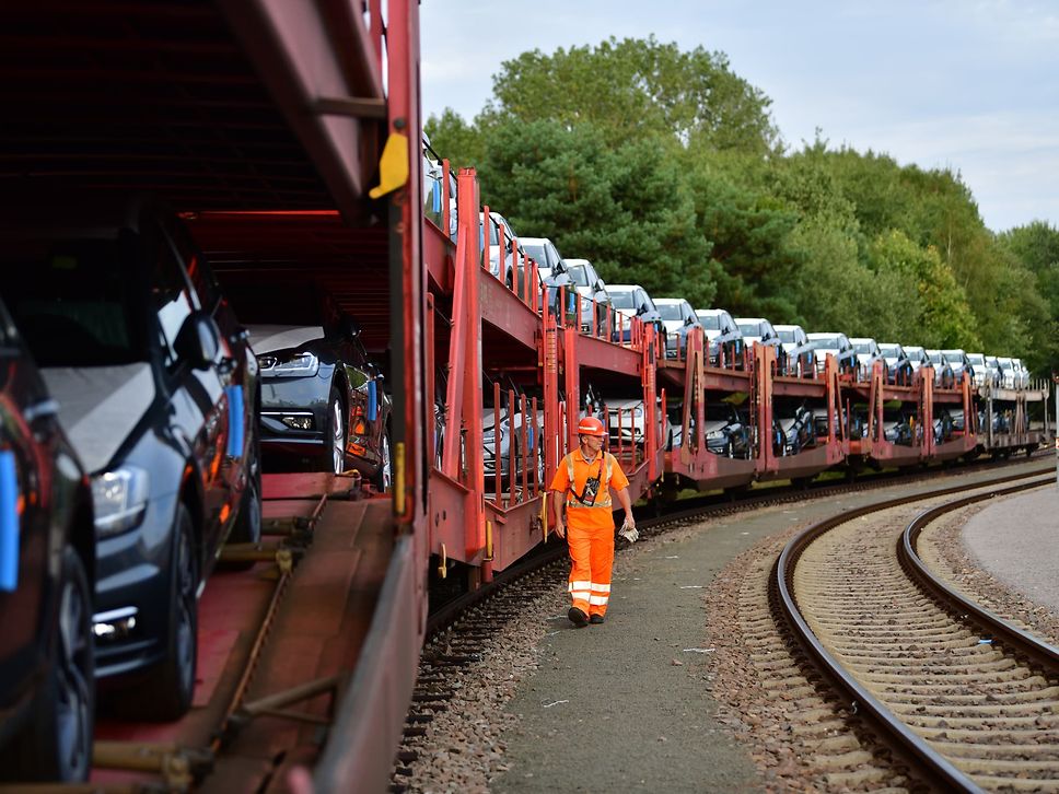 A DB Cargo employee walks alongside a car train.
