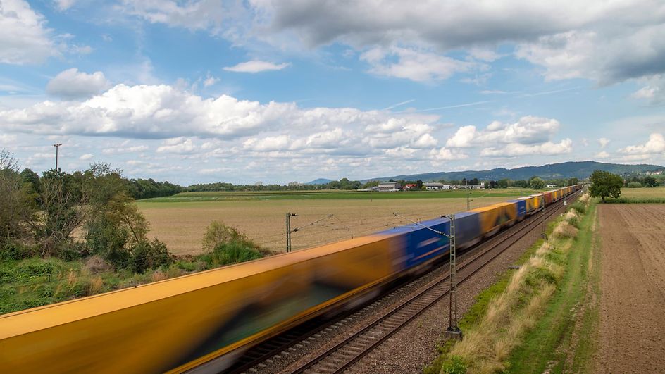 Ein mit mehreren Containern beladener Güterzug von DB Cargo fährt über eine Brücke.