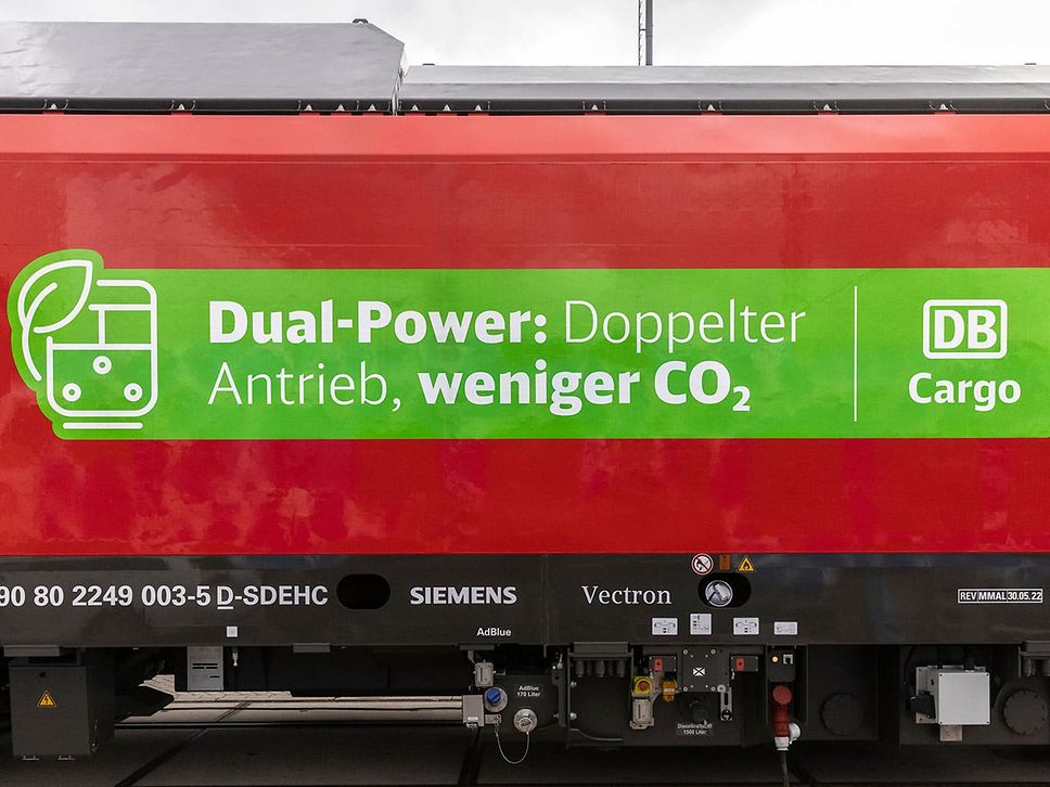 A close-up of a dual-mode locomotive from the side with the lettering "Dual-Power: Double the drive, less CO2" in German.