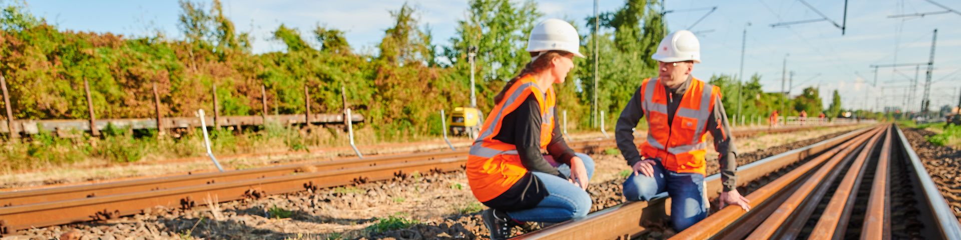 Zwei DB-Mitarbeitende hocken an den Gleisen, neue Gleise liegen vor ihnen.