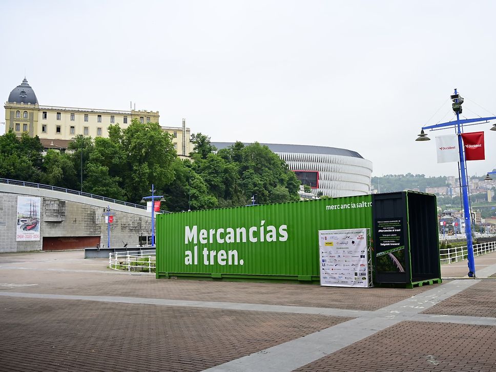 A green freight container labelled "Mercancias al tren" in a square in Bilbao.
