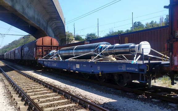 A rotor on a DB Cargo flat car running between other freight cars in a single freight train.