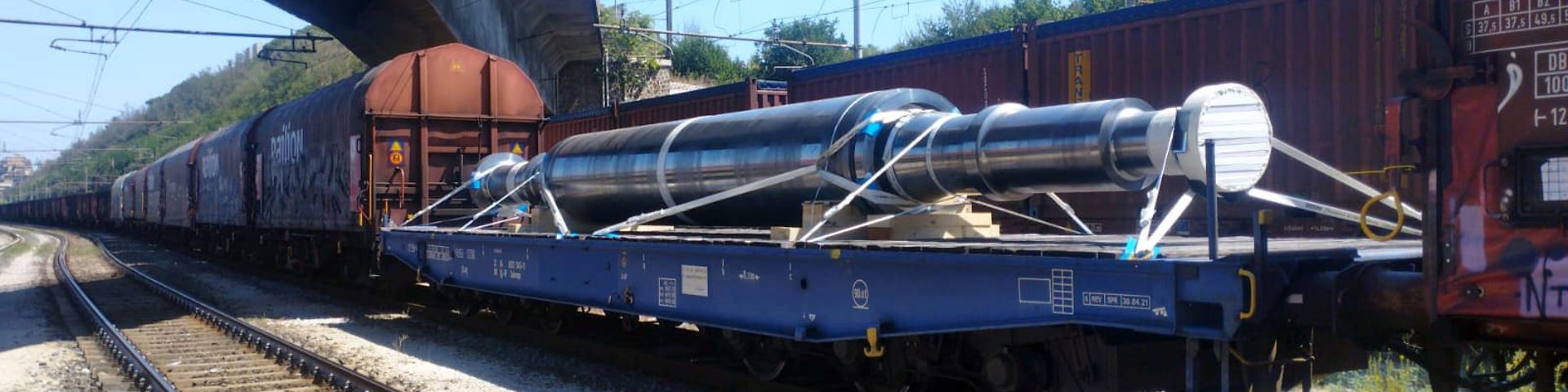 A rotor on a DB Cargo flat car running between other freight cars in a single freight train.