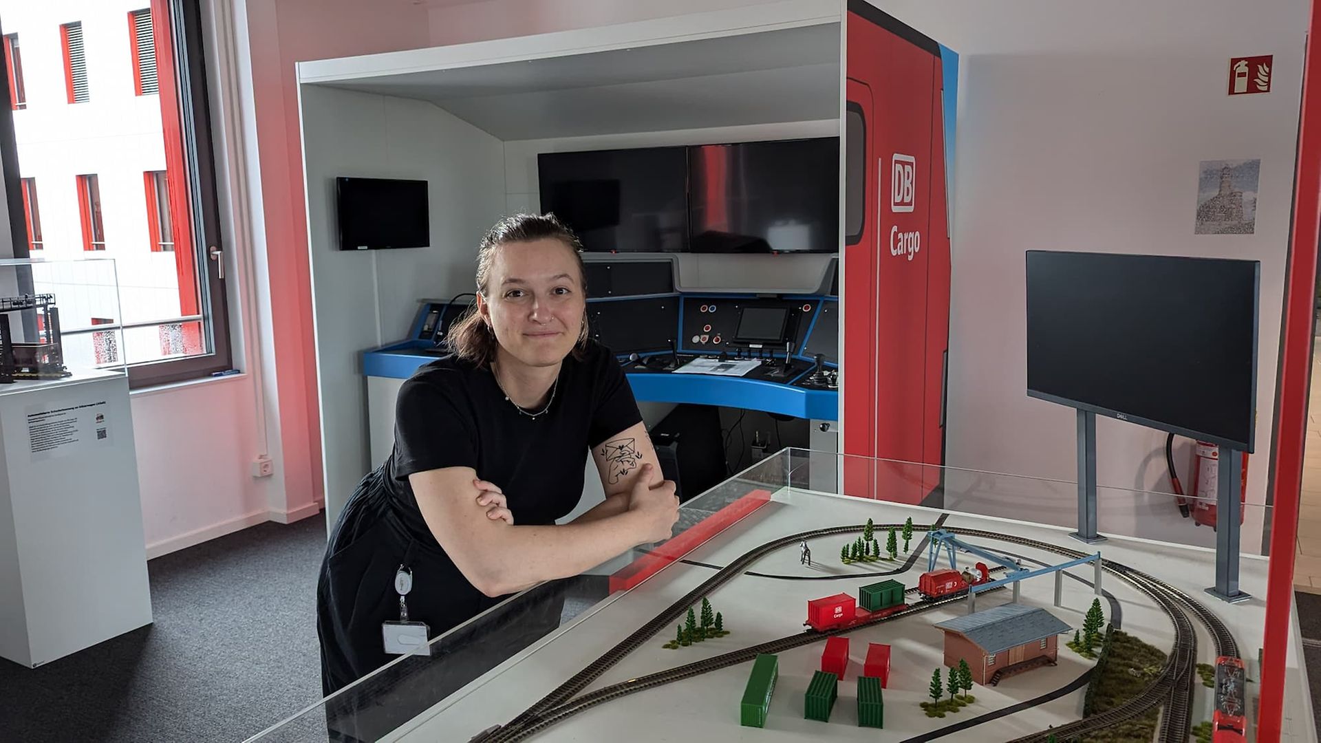 Eine Frau in dunkler Kleidung lehnt auf einer Glasvitrine mit einer Miniatureisenbahn.