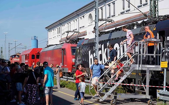 Besucher betrachten auf einem Bahnhofsfest eine Lok von DB Cargo.