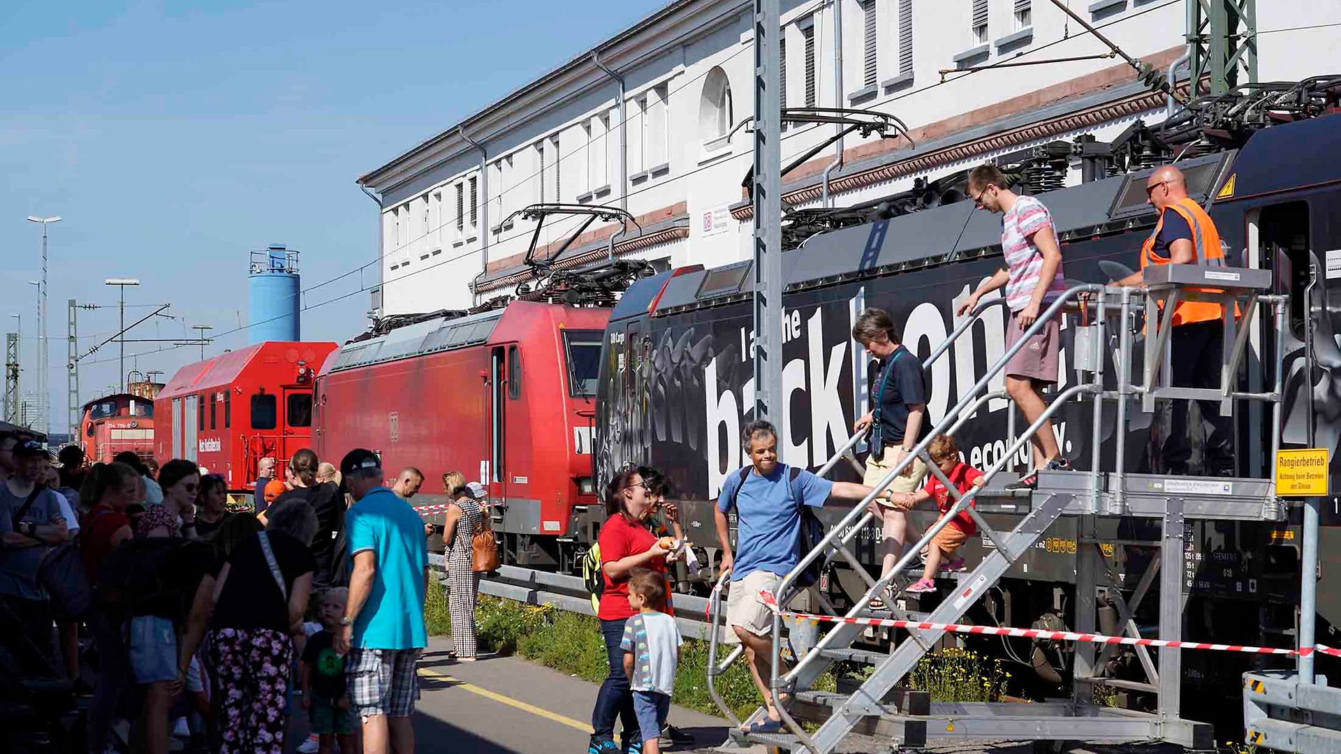 Besucher betrachten auf einem Bahnhofsfest eine Lok von DB Cargo.