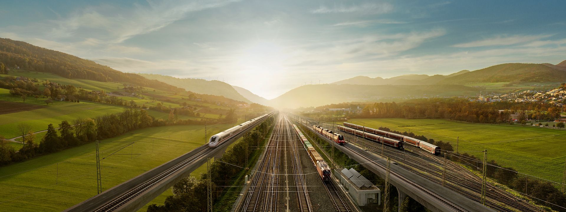 Eine Landschaft mit Horizont, an dem die Sonne aufgeht. Schienen mit verschiedenen Zügen laufen darauf zu und davon weg.