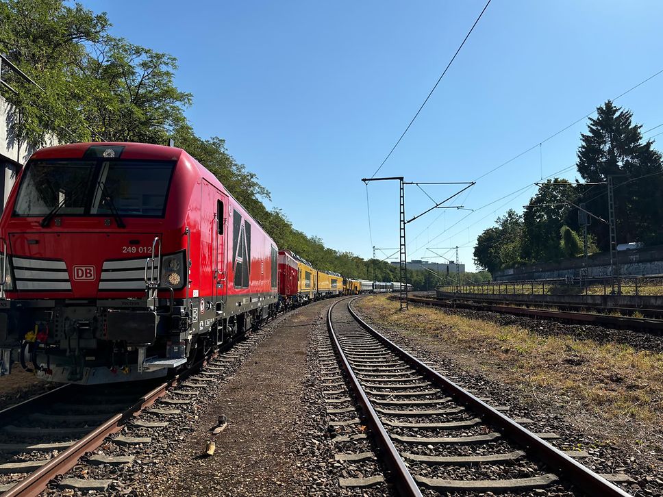 Eine Hybrid-Lok zieht mehrere Ausstellungsstücke für die InnoTrans über Gleise. 