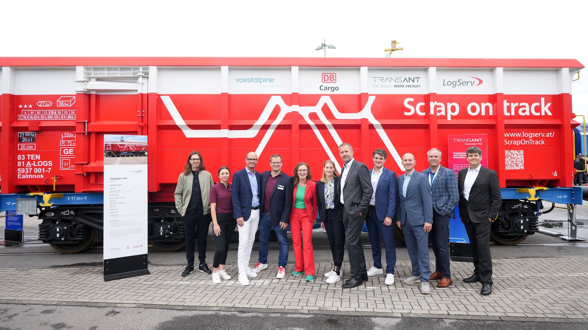 11 people in front of a red freight car at InnoTrans 2024.