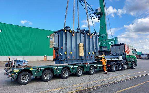 A transformer is loaded onto a truck by crane.