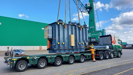 A transformer is loaded onto a truck by crane.