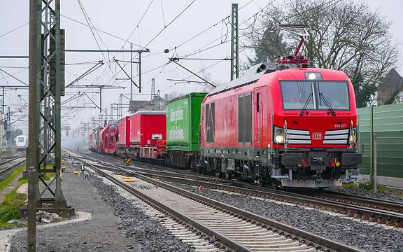 Güterzug mit verschiedenen Güterwagen fährt über die Trasse der sanierten Riedbahn.