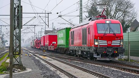 Güterzug mit verschiedenen Güterwagen fährt über die Trasse der sanierten Riedbahn.