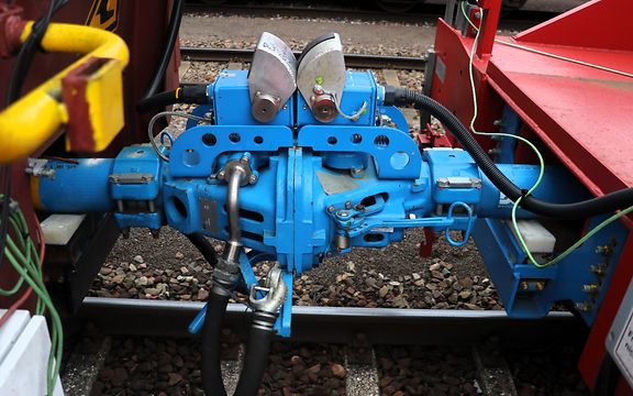 Eine hell-blaue automatische Kupplung zwischen zwei Güterwagen von DB Cargo. 