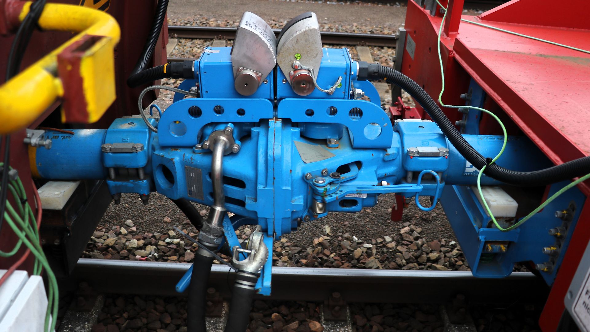 A light blue automatic coupler between two DB Cargo freight cars. 