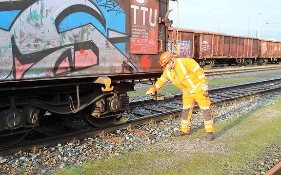 Rangierarbeiter Sebastian Pöther steht im Rangierbahnhof am Gleis an einem abgebremsten Güterwagen