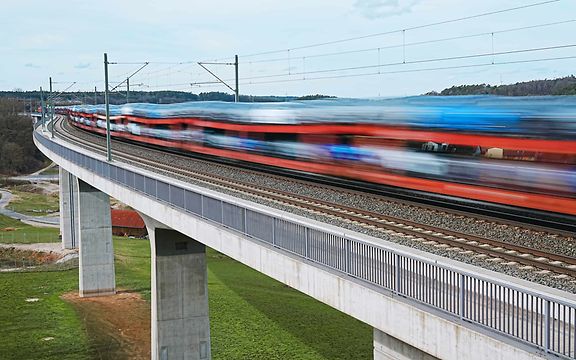 Car transport train crosses bridge